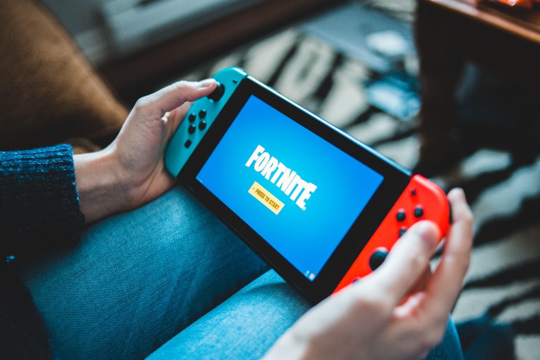 Woman holding a switch on her lap and the screen shows the game Fortnite