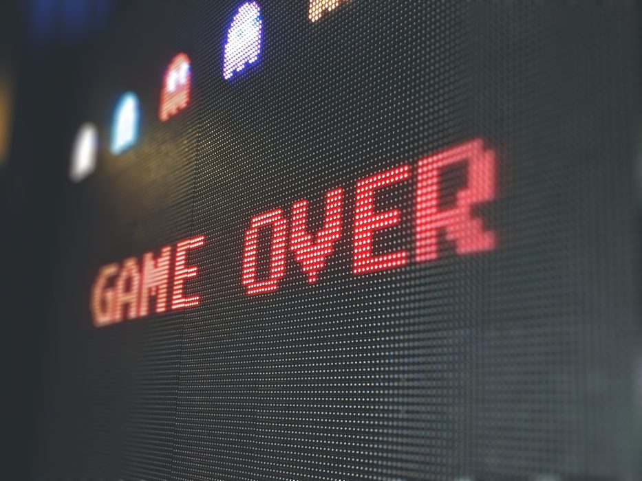 Game over written on a screen, it has some ghosts from the pacman game above.
